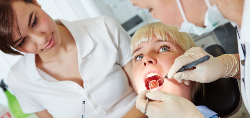 Female patient with dentist and assistant in a dental treatment,